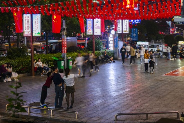 10月2日夜晚,娄底市春园路步行街,市民用手机拍国旗下的全家福.